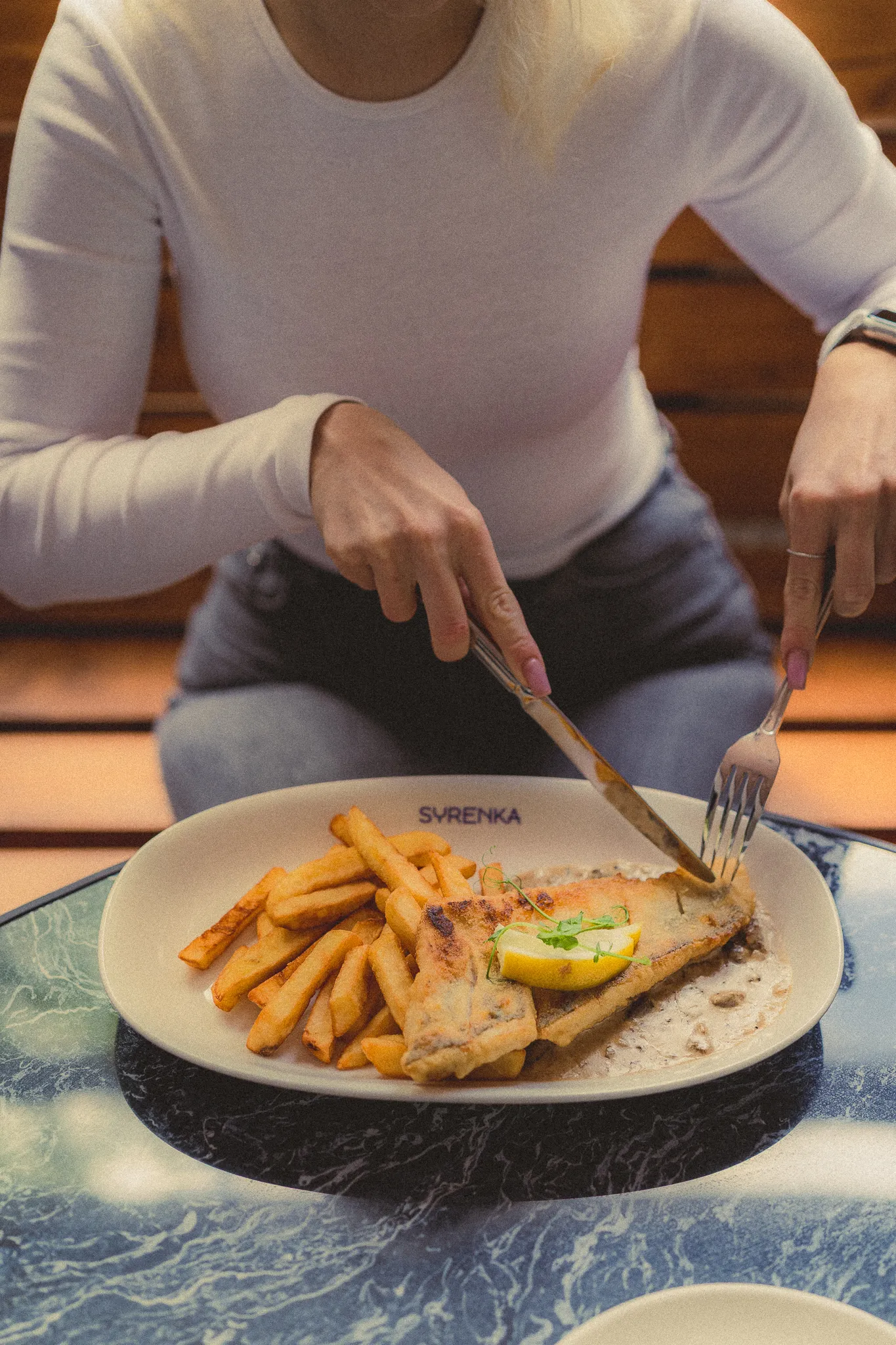 Osoba jedzaca rybe z frytkami - Restauracja Syrenka Kołobrzeg